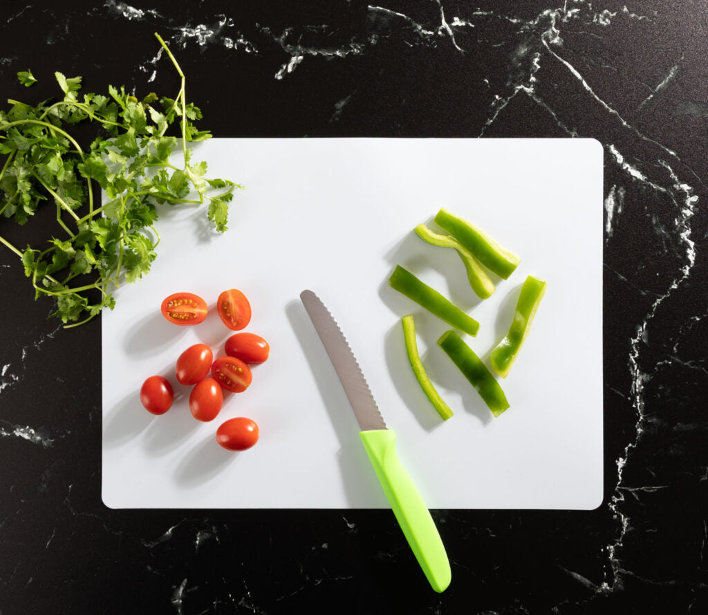 Disposable cutting board in use with knife and vegetables - The Closeout Connection