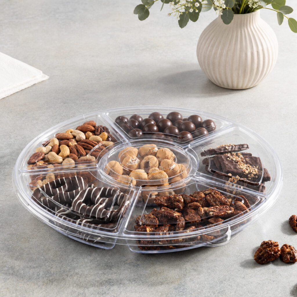 Clear lid on a 6 section round tray filled with nuts and chocolates